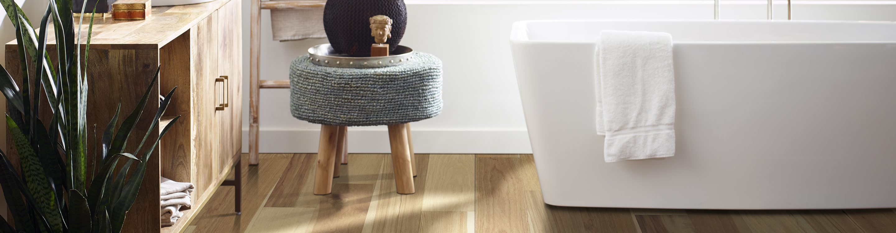 light waterproof hardwood flooring in bathroom with white soaker tub and grey stool